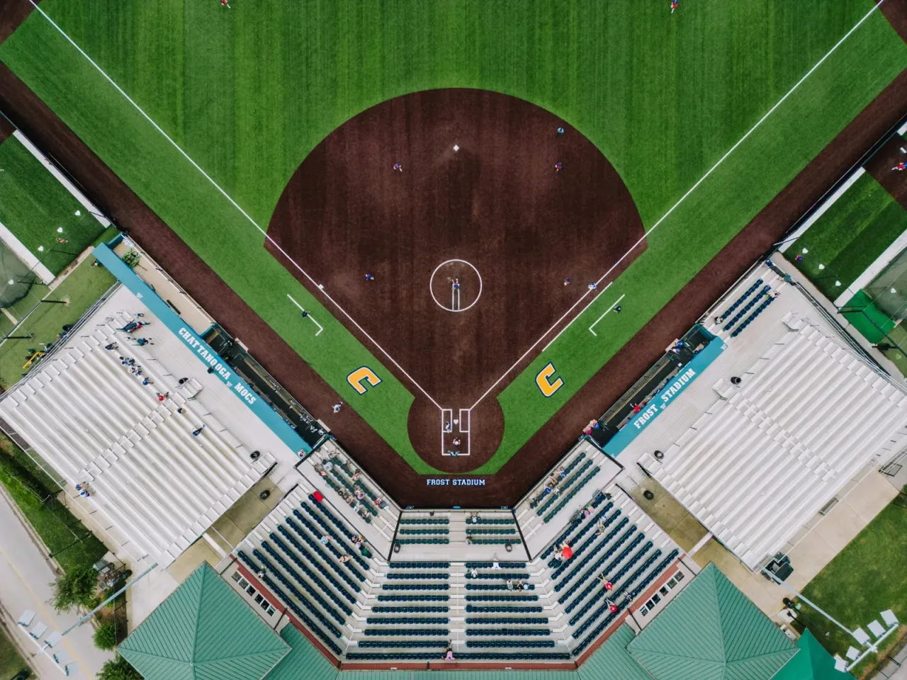 Aerial view of a college baseball diamond with stadium seating visible in the foreground