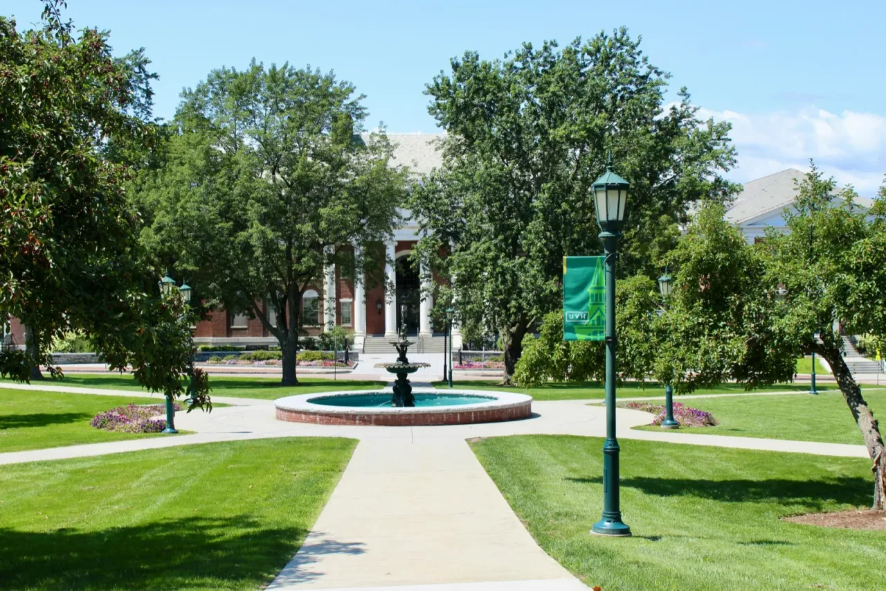 A college campus quad with a fountain and brick buildings in summer