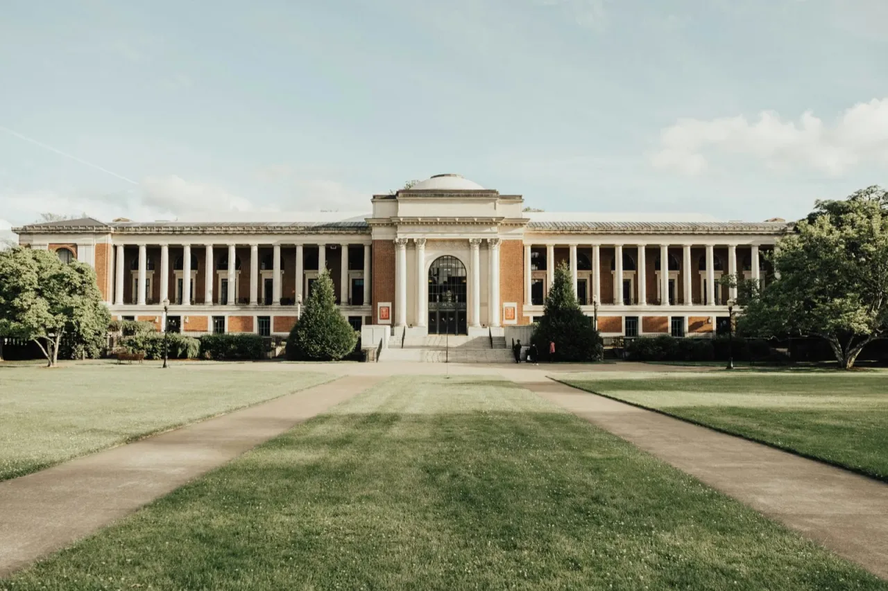 A classical university building with columned entrance and dome on a green lawn