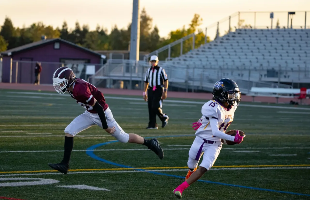A football receiver catching a pass at sunset in a stadium