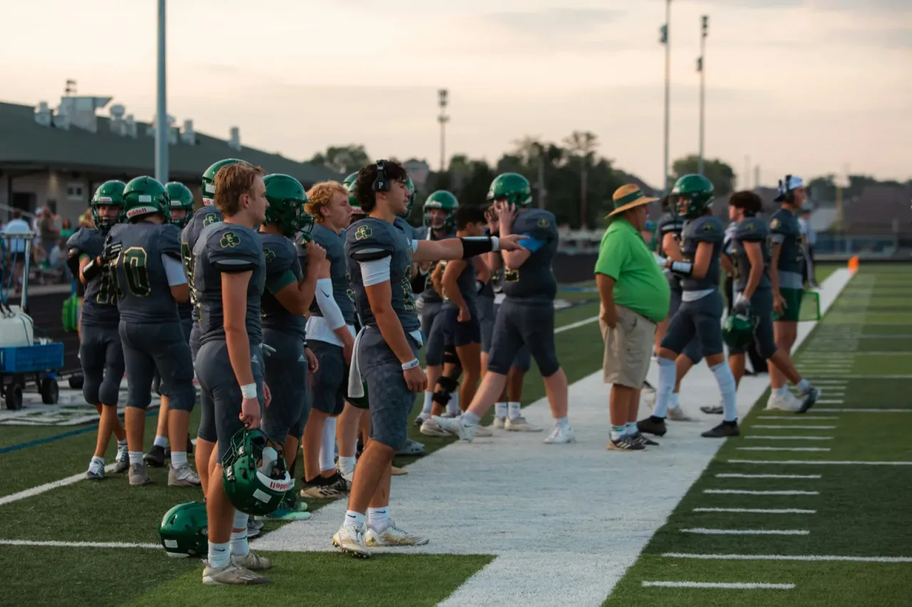 College football players and coaches standing on the sideline during a game