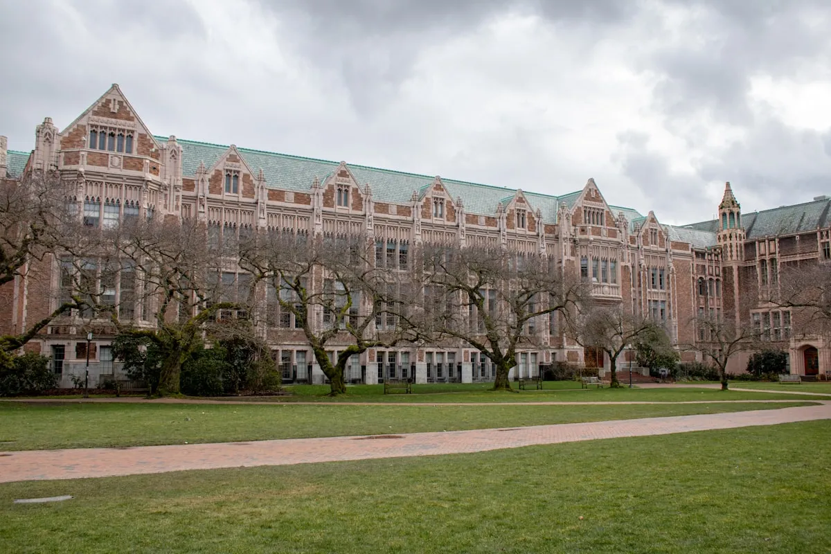 A stately college campus building with brick walls and trees in a campus setting