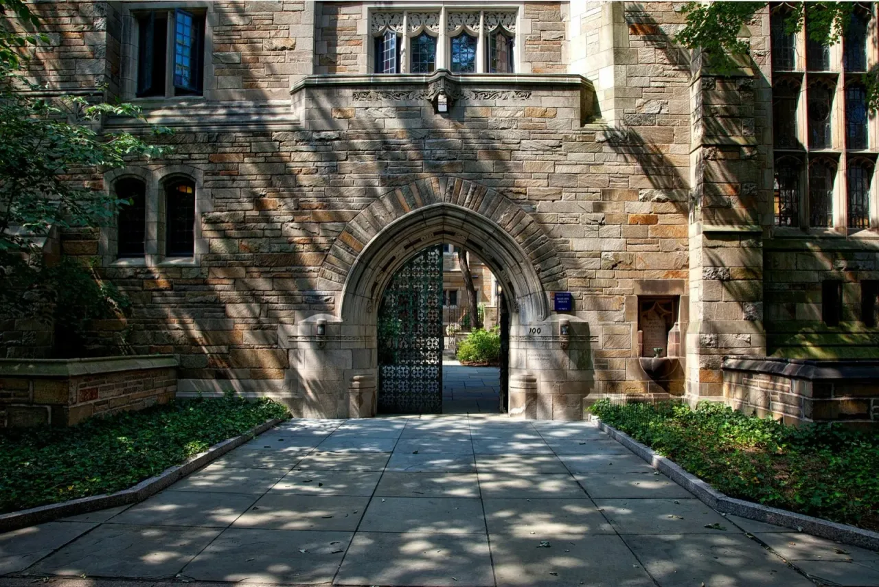 A gothic stone archway entrance to a college campus