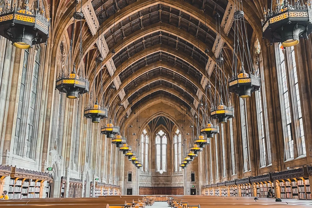 Interior of a grand university library with vaulted wooden ceilings and hanging lanterns