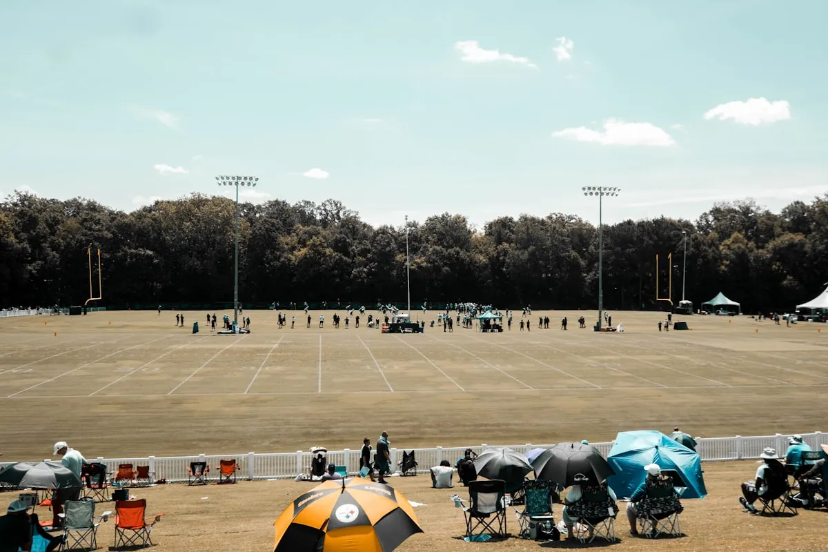 College football players practicing on an outdoor field during a rainy session