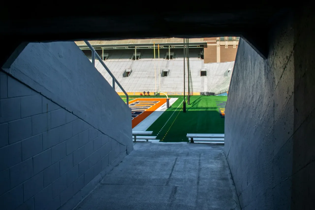 View from a stadium tunnel onto a college football field before kickoff