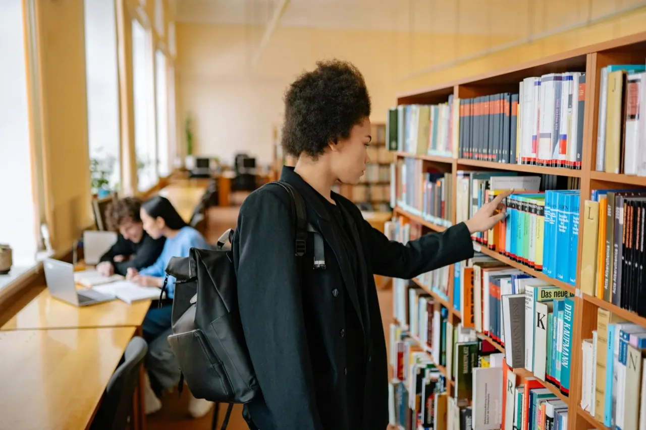 A student reviewing books in a university library