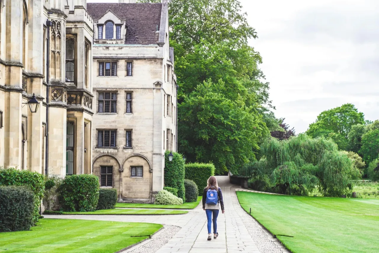 A student walking along a pathway toward a college campus building